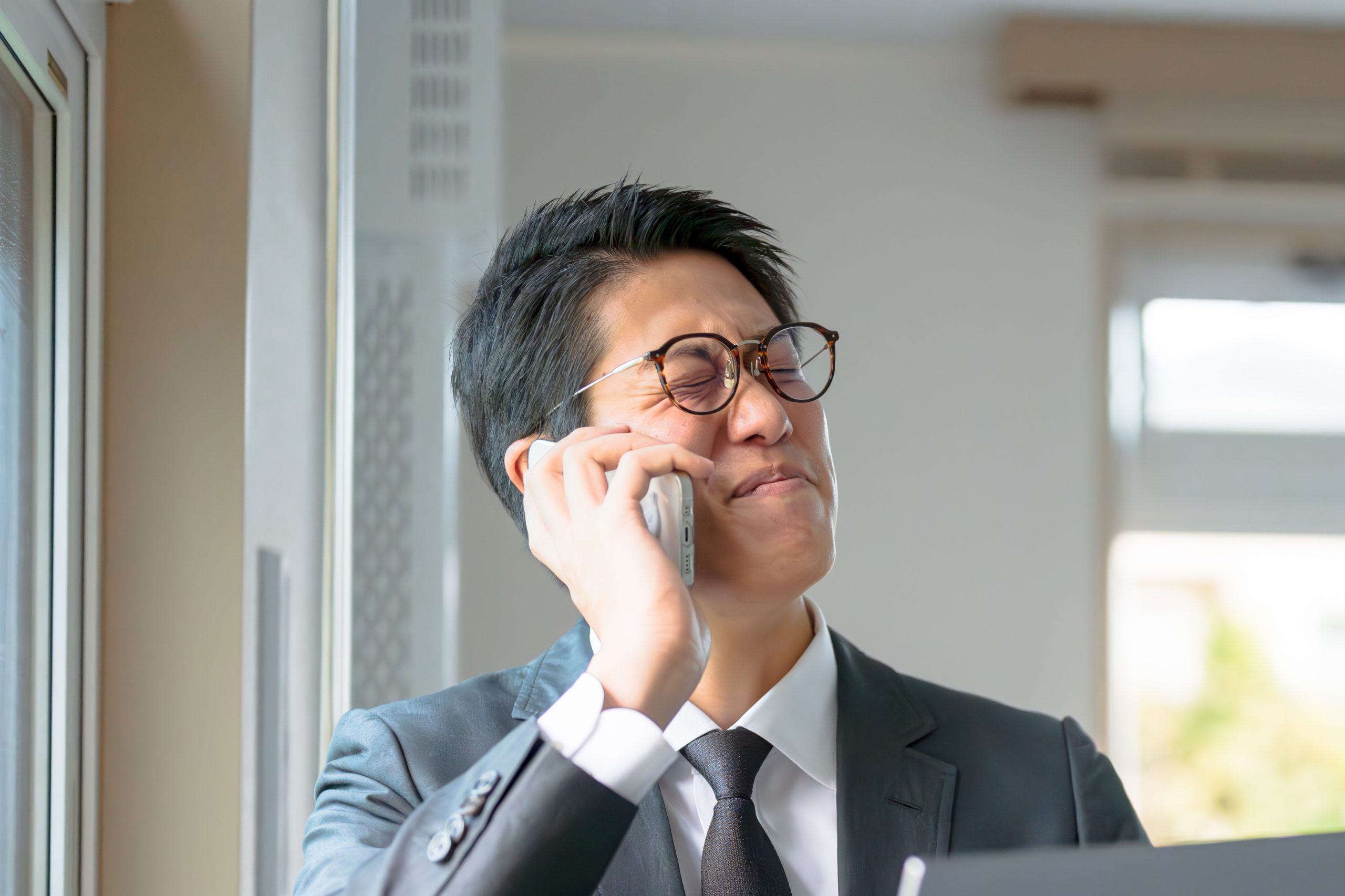 電話中顔を歪めるビジネスマン